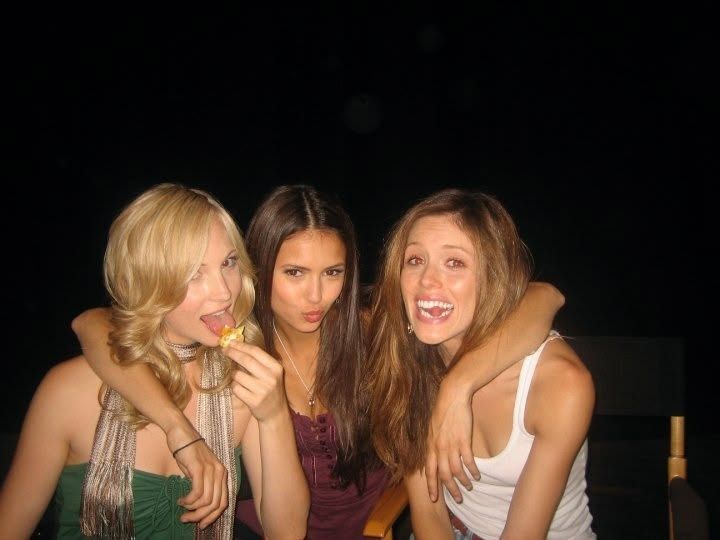 three girls posing for a flash photo at night